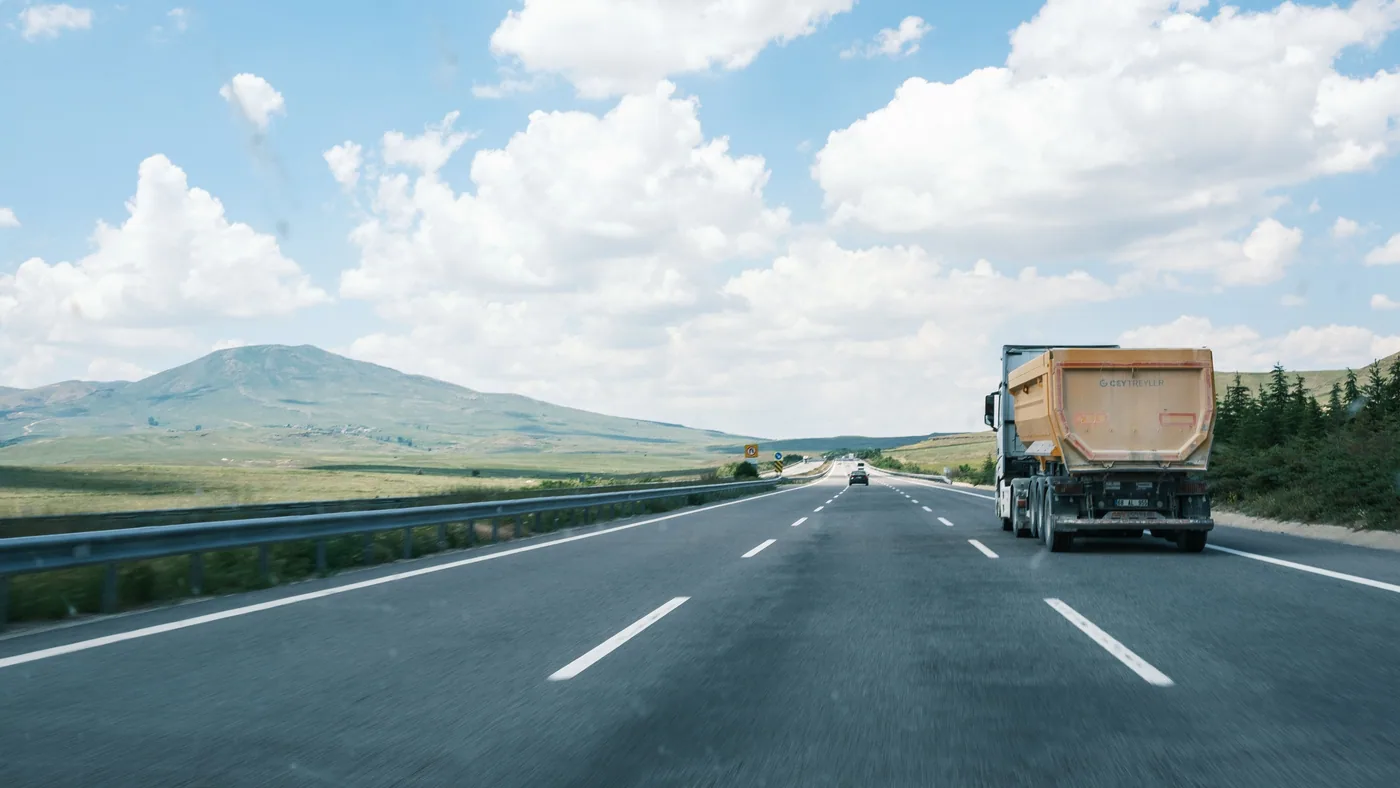 Freight trucks travelling through a scenic highway landscape